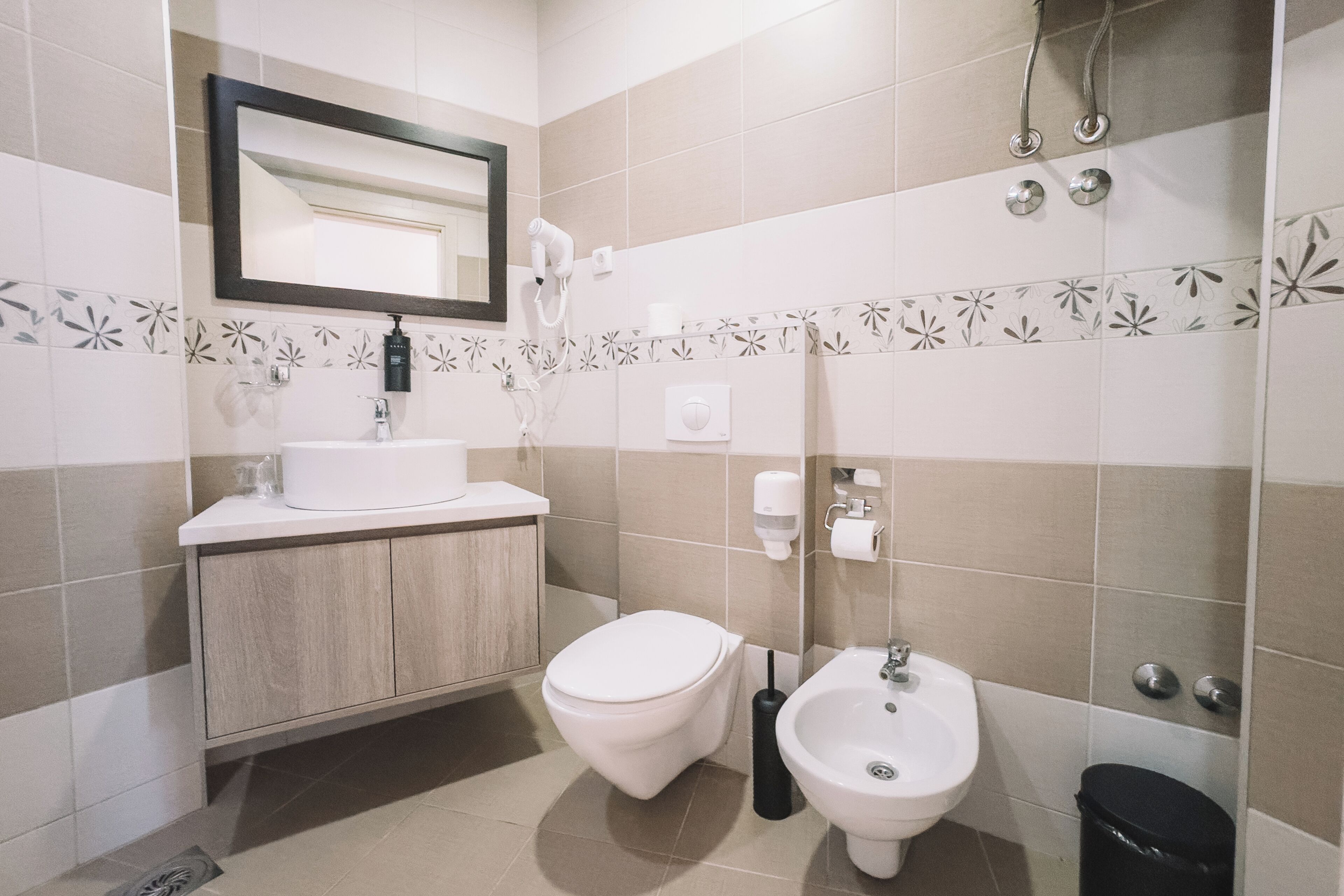 A modern bathroom with a toilet, bidet, sink, and shower.