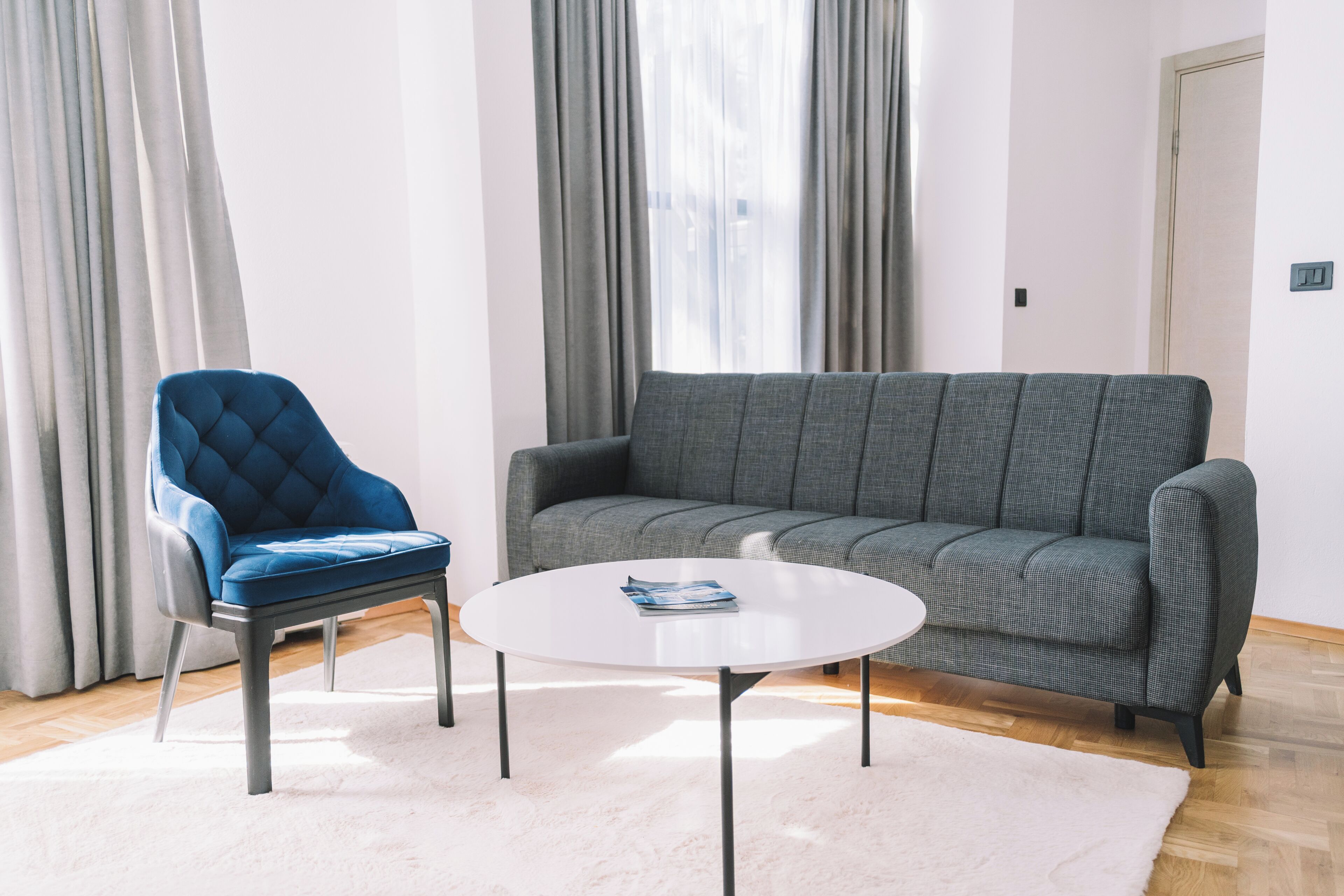 A living room with a blue chair, grey sofa, and a white coffee table.