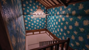 A staircase with wooden railings, a patterned wall, and a hanging light fixture. - Organic Luxury Villa with Infinity Pool & Ocean Views (Karangasem)