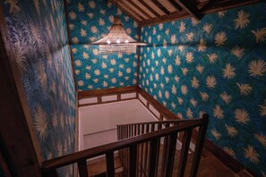A staircase with wooden railings, a patterned wall, and a hanging light fixture. - Organic Luxury Villa with Infinity Pool & Ocean Views (Karangasem)