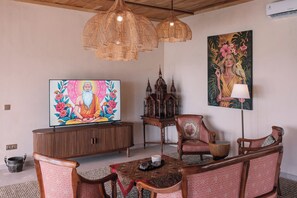 A room with a television, wooden furniture, a painting, and a birdcage. - Organic Luxury Villa with Infinity Pool & Ocean Views (Karangasem)