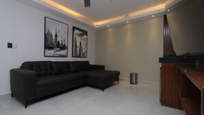 Una sala moderna con un sofá modular, un mueble de madera y dos cuadros con vistas a la ciudad.