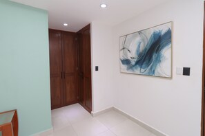 Ein Flur mit einer Holztür, einer weißen Wand mit einem blauen abstrakten Gemälde und einem gefliesten Boden.