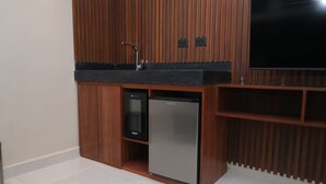 Una cocina compacta con refrigerador empotrado, un lavamanos y un televisor.