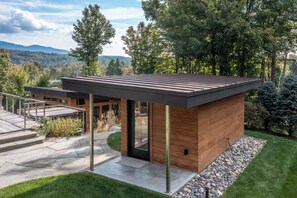 Ein modernes Haus mit flachem Dach, Holzfassade und einem Steinweg, der zu einer Glasdoor führt.