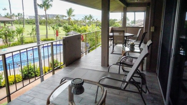 Un balcon avec une piscine, des chaises et une table.