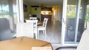 Un coin repas avec une table et des chaises, une cuisine à l’arrière-plan et une porte-fenêtre coulissante donnant sur un espace extérieur.