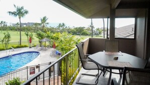 Un balcon avec piscine, un espace salon extérieur et une vue sur un terrain de golf.