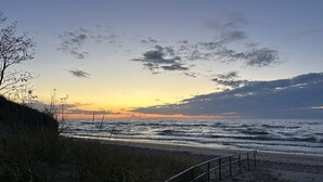 A beach with a metal railing, waves, and a sunset.