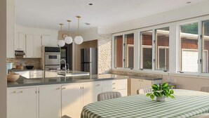 Una cucina moderna con mobili bianchi, elettrodomestici in acciaio inossidabile e un'ampia finestra.