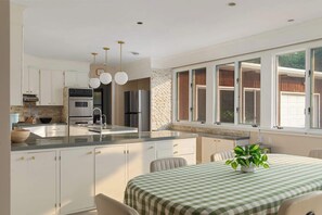 A modern kitchen with white cabinets, stainless steel appliances, and a large window. - RetroRetreat on the Preserve | Dunes/Games/FirePit (South Haven)