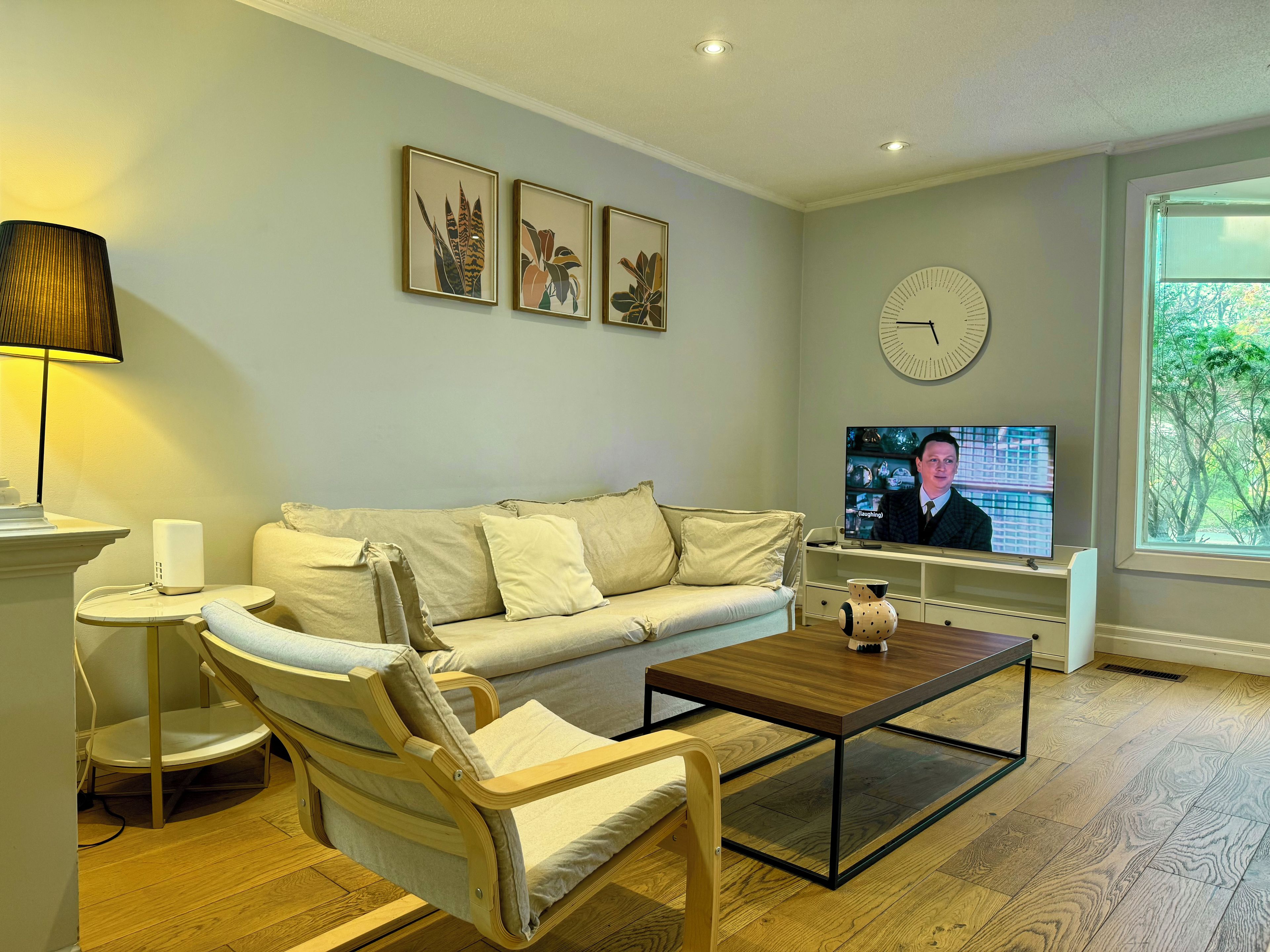 A modern living room with a sofa, armchair, coffee table, and a television.