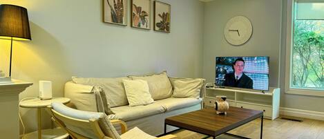 A modern living room with a sofa, armchair, coffee table, and a television.