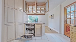 A kitchen with white cabinetry, a dishwasher, and a window with a view of greenery. - Cozy three bedrooms in Scarborough (Toronto)