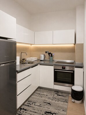 Eine moderne Küche mit einem Edelstahlkühlschrank, einem Backofen, einer Spüle und einem Wasserkocher.
