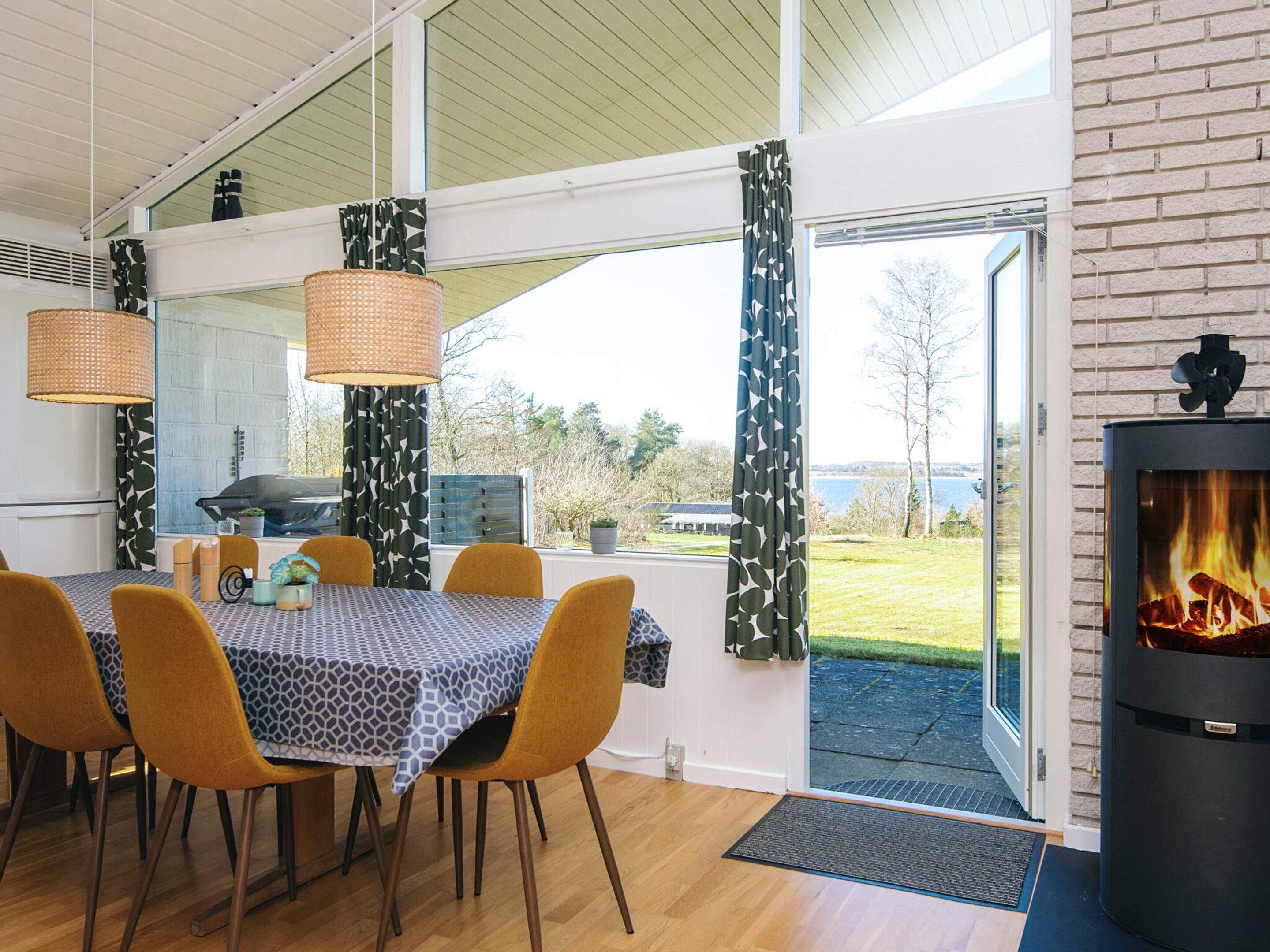 Uma área de refeições com mesa e cadeiras, lareira e vista para o exterior.