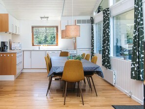 A modern kitchen with white cabinets, a dining table with chairs, and a large window with a view of greenery. - 7 Person Holiday Home in Skals (Skals)