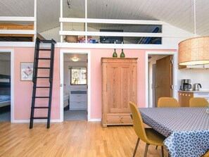A loft-style room with a wooden ladder, a dining table with chairs, a cabinet, and a hanging light fixture. - 7 Person Holiday Home in Skals (Skals)