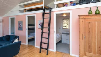 Un dormitorio estilo loft con una escalera de madera, camas literas, un escritorio y un armario.