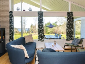 A modern living room with a fireplace, large windows, and a view of the outdoors. - 7 Person Holiday Home in Skals (Skals)