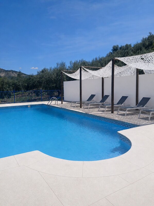 A swimming pool with a white deck, sun loungers, and a white pergola. - Rural house located in the heart of the Natural Park of the Sierras Subbeticas. (AN)