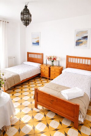 A bedroom with two wooden beds, a nightstand with a vase of flowers, and a hanging lantern. - Rural house located in the heart of the Natural Park of the Sierras Subbeticas. (AN)