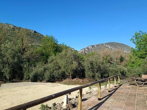 A paved walkway with wooden railings, surrounded by dense greenery and rocky hills. - Rural house located in the heart of the Natural Park of the Sierras Subbeticas. (AN)