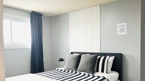 A neatly made bed with striped bedding, a bedside lamp, and a sign indicating quiet hours.