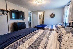 Une chambre avec deux lits, une télévision, une horloge et une armoire.