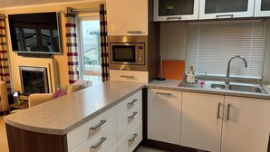 A modern kitchen with a microwave, oven, and double sink. - Iris Lodge, 3 bedroom, dogs stay free at Rockley Park, Poole Harbour, Dorset (Poole)