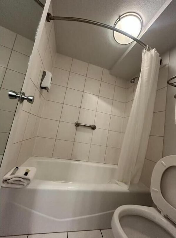 Un baño con bañera, inodoro y cortina de ducha.