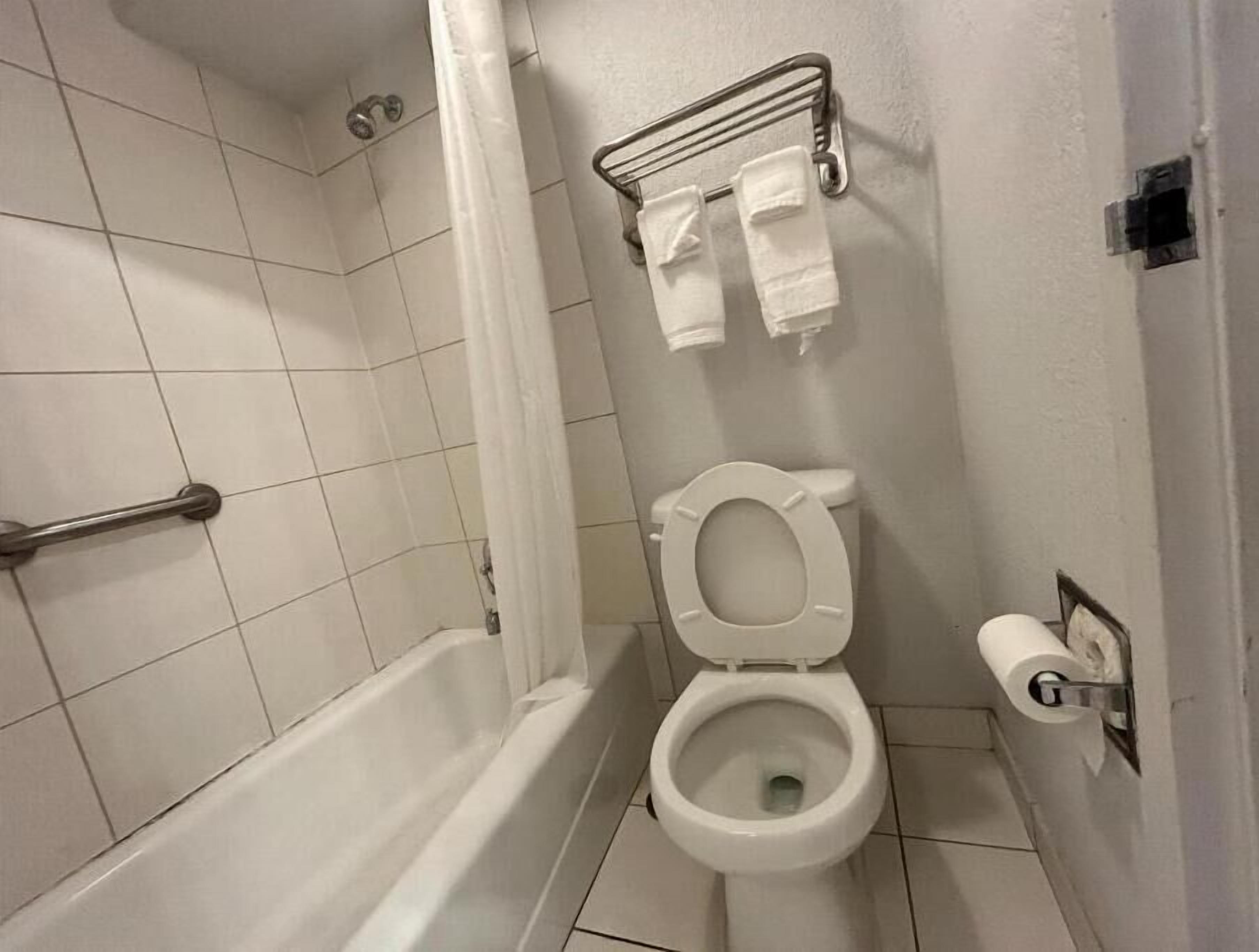 Un baño con inodoro blanco, zona de ducha y toallero con dos toallas.