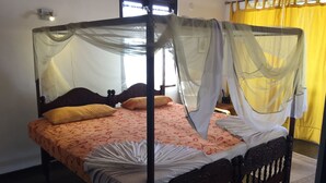 Ein Himmelbett mit Baldachin, einem Holz-Kopfende und einer gemusterten Bettdecke.