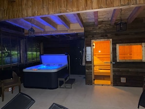 Ein Holzblockhaus-Interieur mit Whirlpool, einer Bank und einer Tür zu einem Außenbereich.
