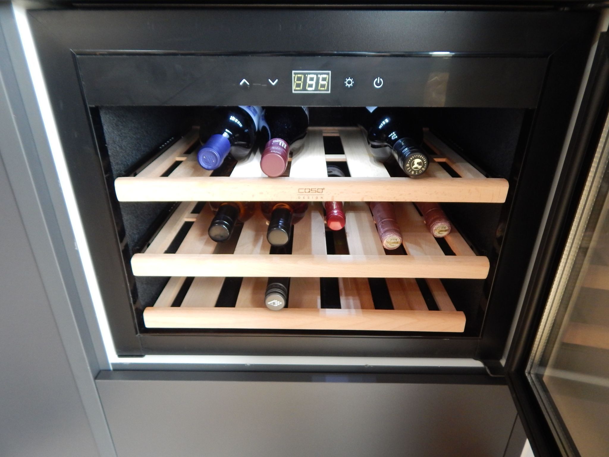 Un enfriador de vinos con varias estanterías que contienen botellas.