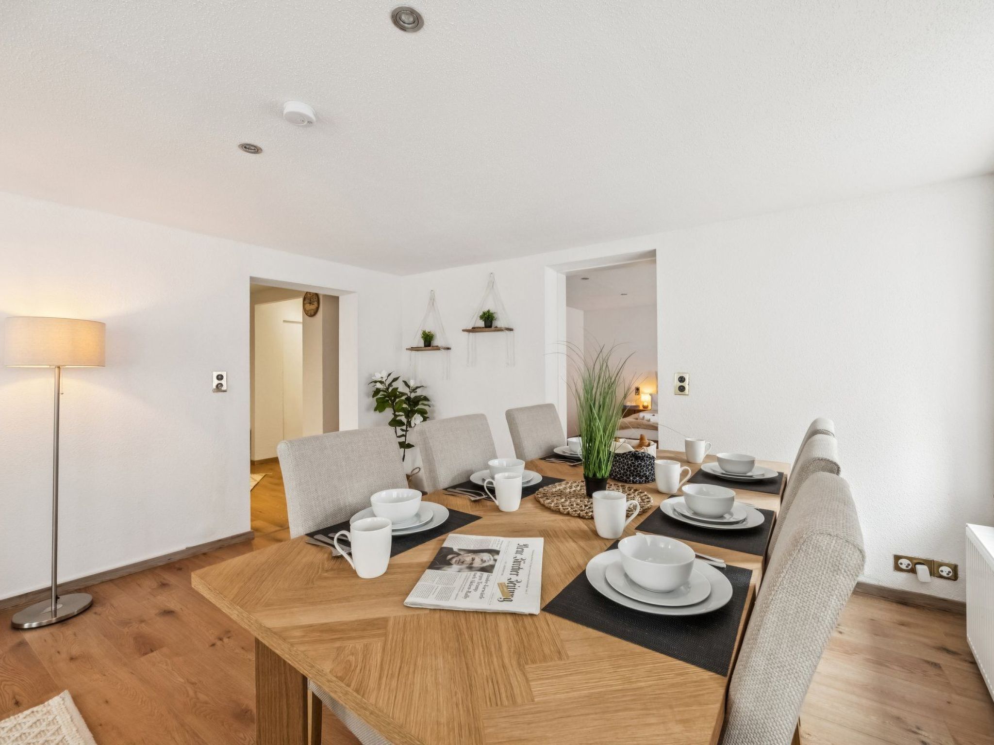 A modern dining area with a wooden table set for four, surrounded by chairs.