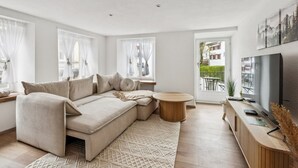 A modern living room with a sectional sofa, a round coffee table, and a TV.