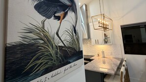Une cuisine moderne dotée d’un plan de travail en marbre, de luminaires suspendus et d’un coin repas avec des chaises.