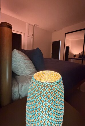 Ein Schlafzimmer mit Bett, Kissen, Lampe und Spiegel.