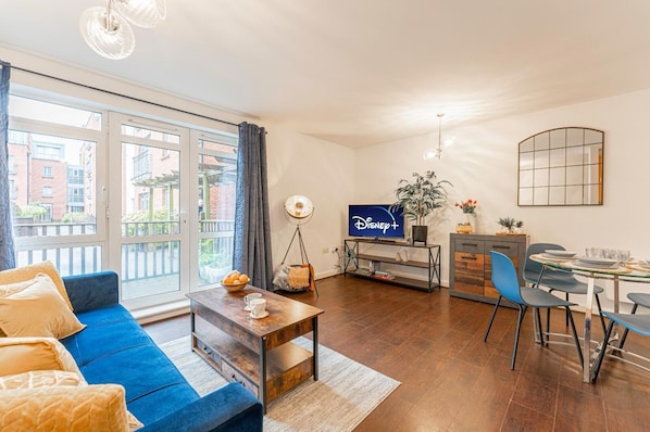 Un salon moderne comprenant un canapé, une table basse, un téléviseur, une table à manger, des chaises et une vue sur le balcon.