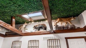 Een kamer met een groen kunstplafond, houten balken en bevestigde dierbeelden.