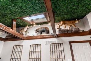 Ein Zimmer mit grüner, künstlicher Decke, Holzbalken und angebrachten Tiermodellen.