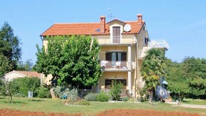 A two-story building with a balcony, a satellite dish, and a garden. - Relaxing Retreat With Terrace (Umag)