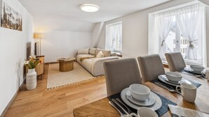 Een moderne, goed verlichte kamer met een eethoek, een bank en een klein bijzettafeltje.