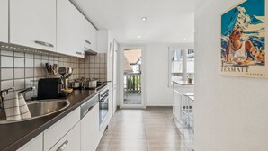 Een moderne keuken met witte kasten, roestvrijstalen apparatuur en een betegelde spatwand.
