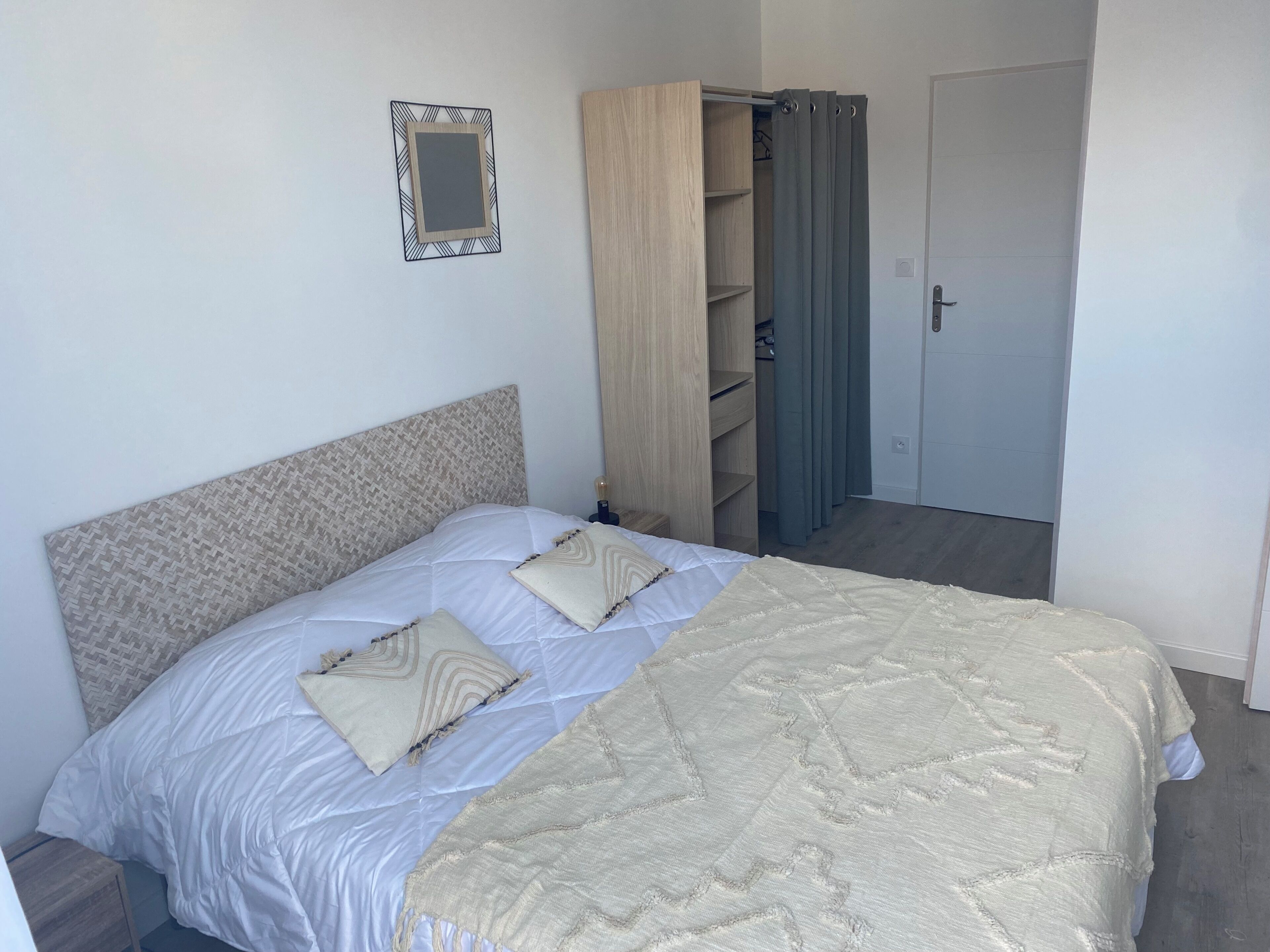 A bedroom with a bed, a wardrobe, a mirror, and a door.