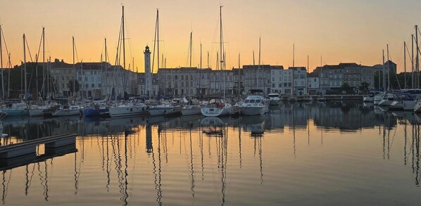 Ein Yachthafen mit mehreren angemeldeten Booten, einem markanten Leuchtturm und Gebäuden entlang der Küste.