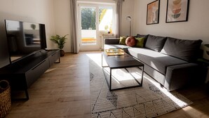 A modern living room with a flat-screen TV, a sofa, a coffee table, and a patterned rug. - Come4Stay Passau - 2 Zimmer - bis zu 4 Gäste by Interhome (Passau)