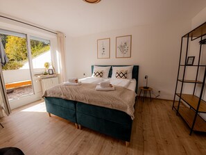 A bedroom with a bed, a bedside table, a radiator, and a window. - Come4Stay Passau - 2 Zimmer - bis zu 4 Gäste by Interhome (Passau)
