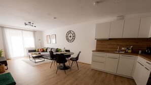 A modern kitchen with white cabinets, a wooden countertop, and a built-in dishwasher. - Come4Stay Passau - 2 Zimmer - bis zu 4 Gäste by Interhome (Passau)